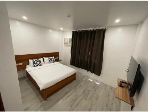 um pequeno quarto com uma cama e uma televisão em The Nook by Garolu em Castillejos