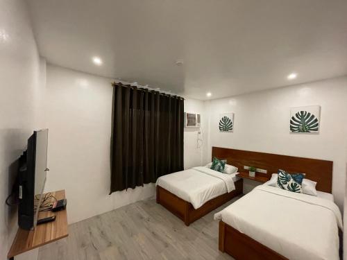 um quarto de hotel com duas camas e uma televisão em The Nook by Garolu em Castillejos