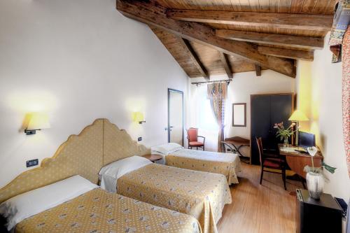 una camera d'albergo con 2 letti e una scrivania di Antica Locanda Il Sole a Castel Maggiore
