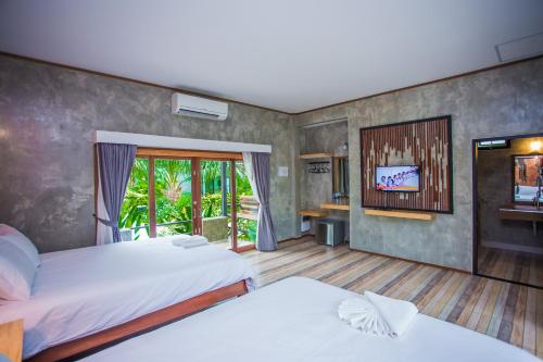 a bedroom with two beds and a flat screen tv at Palm Pran Resort in Pran Buri