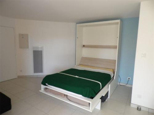 une chambre avec un lit avec une couverture verte dans l'établissement Studio confortable avec terrasse, accès direct plage et parking privé - FR-1-326-506, à Marseillan