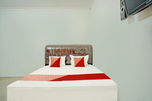 HutamanikにあるOYO 92239 Taman Wisata Iman Iのベッドルーム1室(赤と白の枕が備わるベッド1台付)