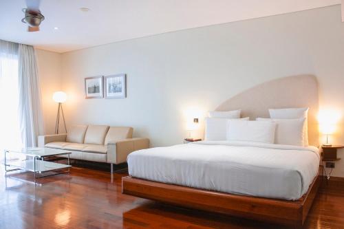 a bedroom with a bed and a couch and a chair at Airways Hotel in Port Moresby