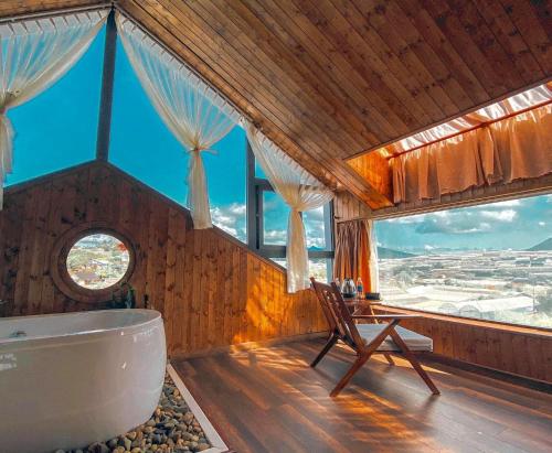 a bathroom with a tub and a chair and windows at Nhà Sói Homestay Da Lat in Da Lat
