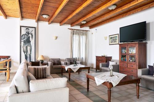 a living room with couches and a flat screen tv at Eva Suites & Apartments in Agia Marina Nea Kydonias