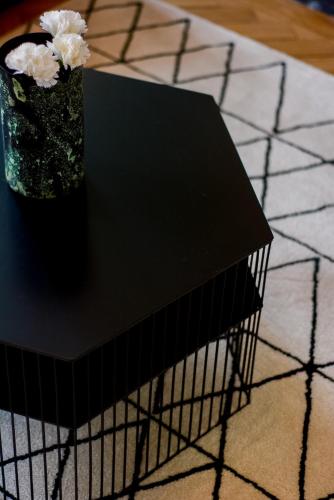 a black table with a vase with flowers on it at - Le Manon !Gare - topappartnancy in Nancy