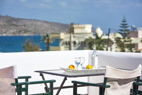 a table with two chairs and a bottle and glasses at Eva Suites & Apartments in Agia Marina Nea Kydonias