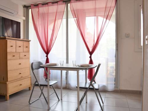 une table et deux chaises dans une pièce avec une fenêtre dans l'établissement Appt cosy avec parking, lave-linge, proche port à Gruissan - FR-1-229-792, à Gruissan