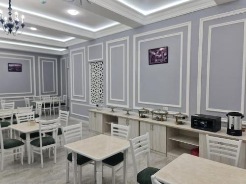 uma sala de jantar com mesas e cadeiras brancas em OLD STATION HOTEL em Samarkand