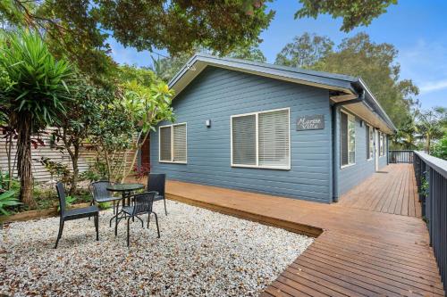 a backyard with a blue house with a wooden deck at Marine Villa in Smiths Lake