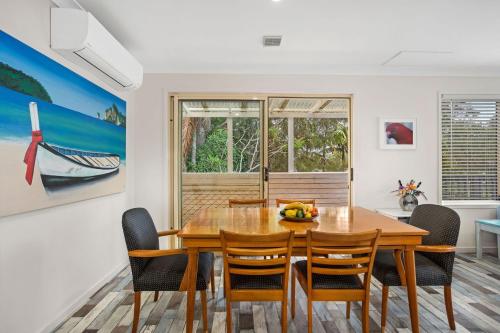a dining room with a wooden table and chairs at Marine Villa in Smiths Lake