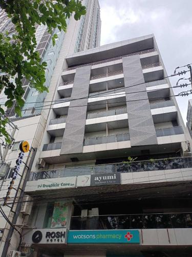 a tall apartment building in a city at Rosh Hotel in Manila