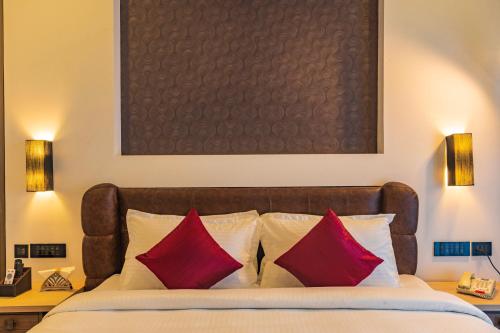 a bedroom with a bed with two red pillows at Classic Regency in Alleppey