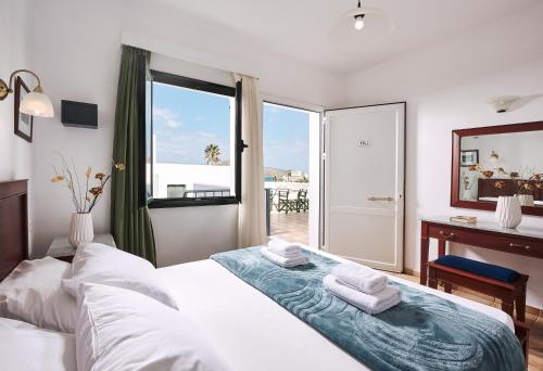 Un dormitorio con una cama y una ventana y un escritorio. en Eva Suites & Apartments, en Agia Marina de Nea Kydonia