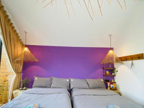 two beds in a room with a purple wall at Nhà Sói Homestay Da Lat in Da Lat
