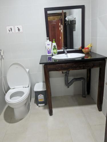 een badkamer met een wastafel, een toilet en een spiegel bij Hoa Anh Đào Garden Hotel in Thuan An