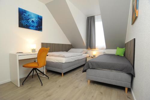 een slaapkamer met 2 bedden, een bureau en een stoel bij Swetis Passage in Pulheim