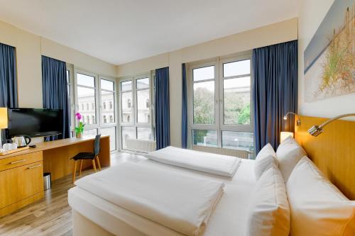 a hotel room with a bed and a desk and windows at Hotel Berlin Mitte by Campanile in Berlin