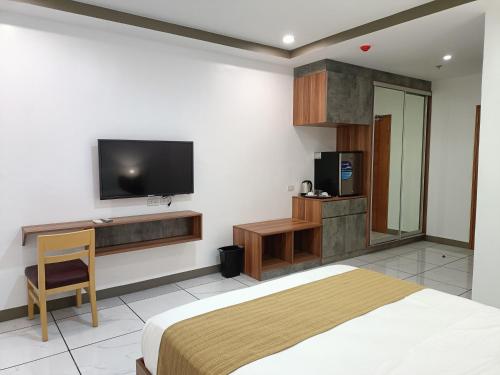 a bedroom with a bed and a tv on the wall at Rosh Hotel in Manila