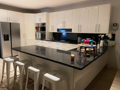 a kitchen with white cabinets and a black counter top at Beach House on Stockton Beach, Newcastle in Stockton