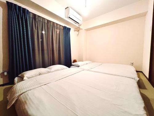 two beds in a room with a window at Love Asakusa 1 Bedroom Apartment Sleeps 6 SkyTree View 3 Min to Sensoji Airport Direct Elevator Free WiFi in Tokyo
