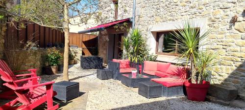 un patio con muebles de color rosa y una silla roja en Villa Misanid écrin de verdure à 15mm de la cité de Carcassonne, en Mas-des-Cours