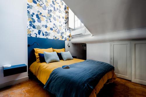 a bedroom with a bed with a blue and yellow blanket at Appart Exceptionnel place du Palais des papes Wifi climatisation in Avignon