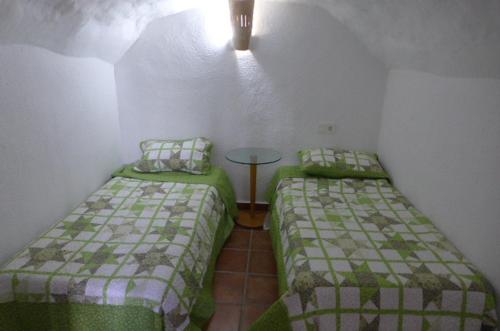 a room with two beds and a table in it at Cuevas Don Alvaro y Romaide 
