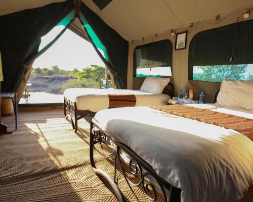 a group of three beds in a tent at Julia's River Camp in Talek