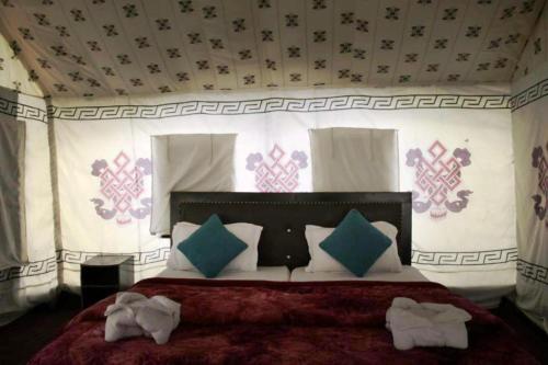 een slaapkamer met een groot bed met kussens bij Nubra Leisure Camp in Leh