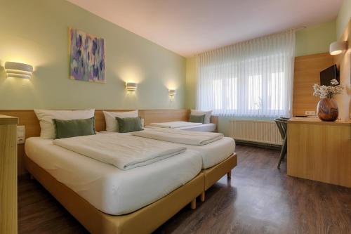 a hotel room with two beds and a desk at Hotel Kunterbunt - by homekeepers in Würzburg