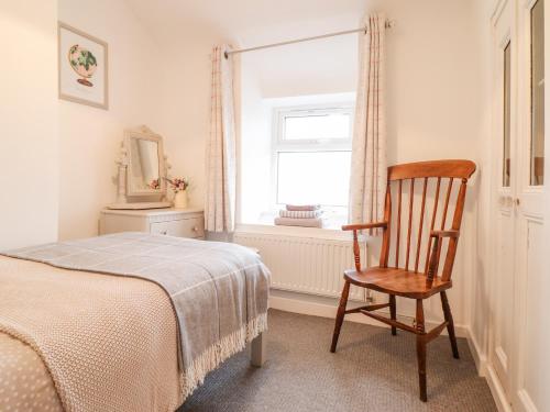 a bedroom with a chair and a bed and a window at 5 Bryn Tirion in Blaenau-Ffestiniog