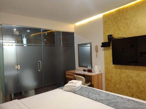 a bathroom with a shower and a bed and a television at Sempre Premier Inn - MACTAN AIRPORT HOTEL in Mactan