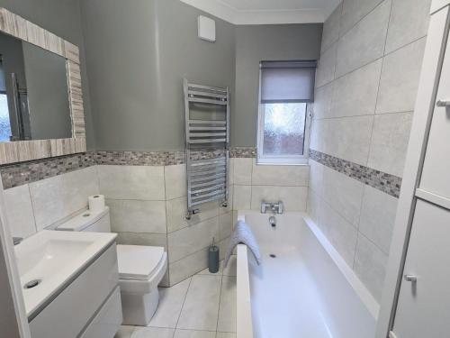 a bathroom with a tub and a toilet and a sink at Lincoln Lodge, 2-bedroom,2-bathroom,ground floor flat in Southend-on-Sea