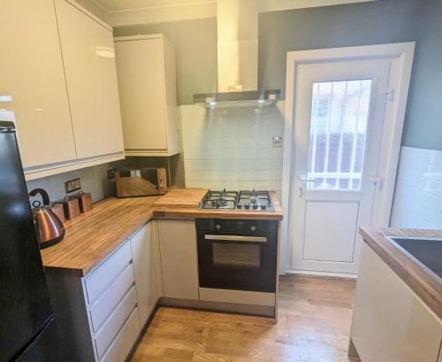 a kitchen with white cabinets and a stove top oven at Lincoln Lodge, 2-bedroom,2-bathroom,ground floor flat in Southend-on-Sea