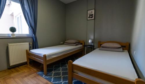 deux lits dans une petite pièce avec une fenêtre dans l'établissement Central Fenix apartment - Free private parking-Fast WI-FI, à Novi Sad