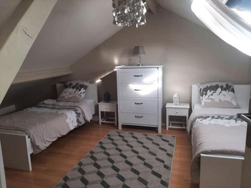 - une chambre mansardée avec 2 lits et une commode dans l'établissement Maison Aubergenville Elisabethville, à Aubergenville