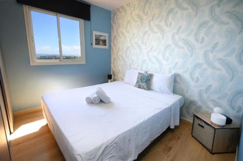 - une chambre avec un lit blanc et un mur bleu dans l'établissement Livianna, appartement 2 personnes avec une magnifique vue mer à Saint-Denis, à Saint-Denis