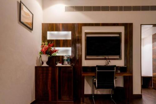 Habitación con escritorio y TV en la pared. en Hotel 5 Flowers Ananta Elite, en Kota