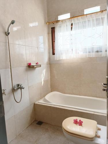 a bathroom with a tub and a toilet and a sink at Meninting garden house in Montongbuwoh