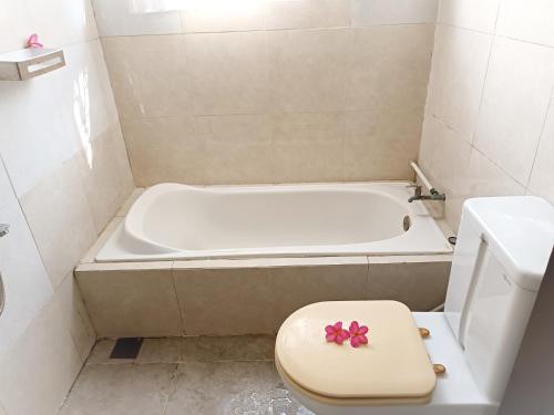 a bathroom with a tub and a toilet with a pink bow on it at Meninting garden house in Montongbuwoh