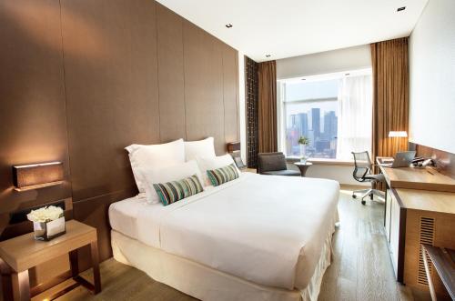 um quarto de hotel com uma cama grande e uma secretária em Nina Hotel Kowloon East em Hong Kong