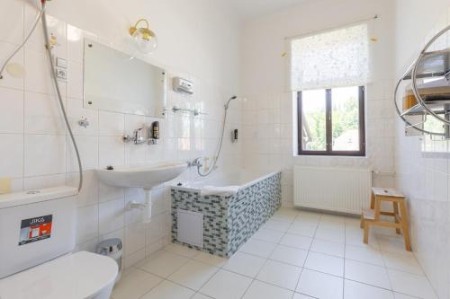 biała łazienka z umywalką i wanną w obiekcie Hotel Amadeus w Czeskich Budziejowicach