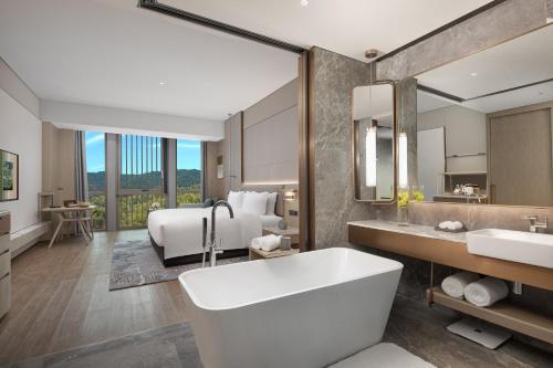 een badkamer met een bad en een slaapkamer met een bed bij Wonderland Hotel Ningbo International Conference Center in Ningbo