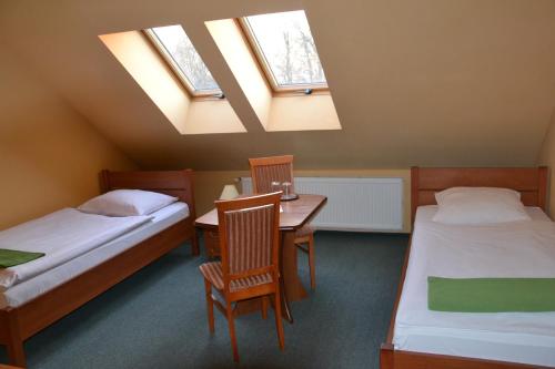 Cette chambre comprend deux lits, une table et des chaises. dans l'établissement Hotelik Orlik, à Legnickie Pole