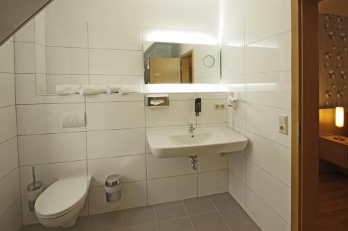 a white bathroom with a toilet and a sink at Gasthaus & Pension Am Kurfürstendamm in Burg