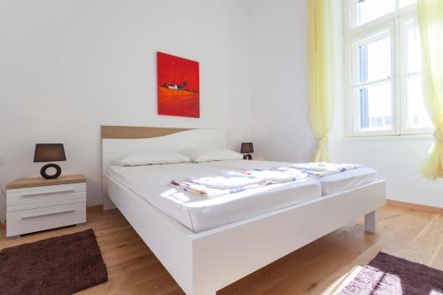 a white bed in a white bedroom with a window at Apartment Red Coral in Dubrovnik