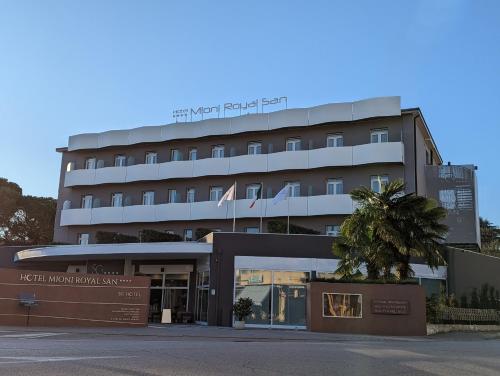 a hotel building with a palm tree in front of it at Hotel Mioni Royal San in Montegrotto Terme