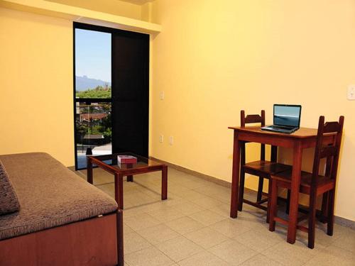 1 dormitorio con escritorio y mesa con ordenador portátil en Scala Residence Hotel, en Resende