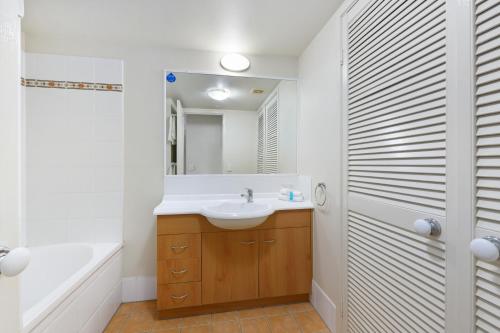 La salle de bains est pourvue d'un lavabo, d'une baignoire et d'un miroir. dans l'établissement BEST Ground Floor pool side Superior apartment - new listing, à Gold Coast